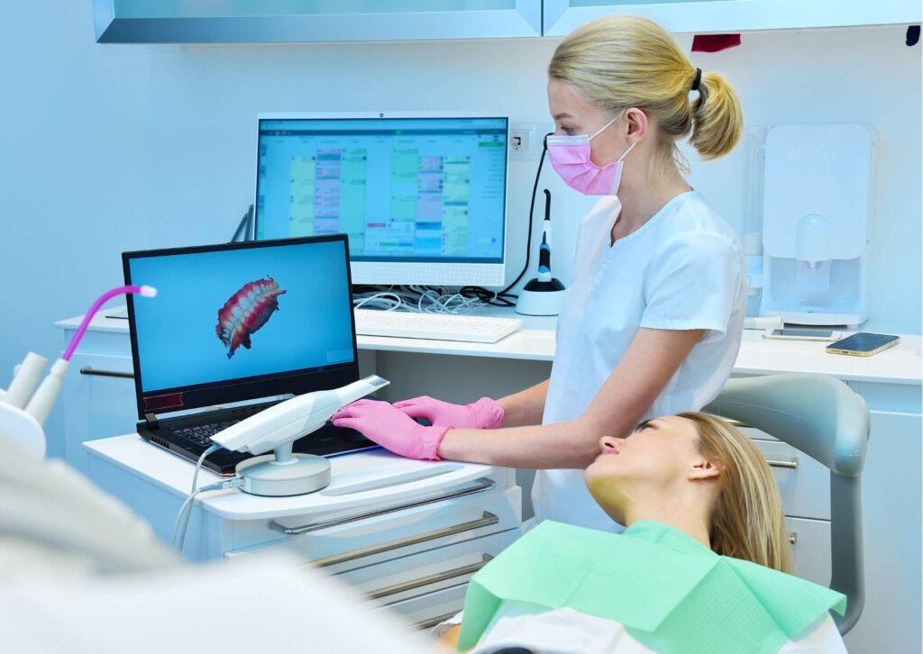 Dentist reviewing a digital smile model with a patient while discussing whether crowns or veneers are the better treatment option.