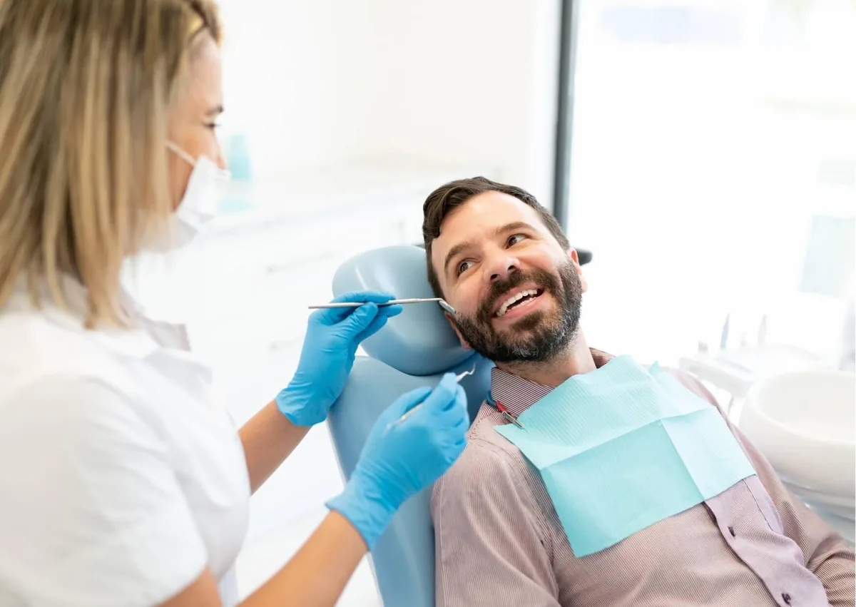 Dentist examining a patient’s teeth to monitor dental implants and support their long-term lifespan.