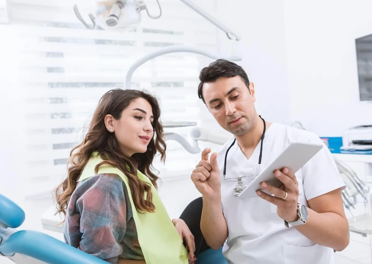 Dentist discussing dental implant treatment options with a patient during a consultation.