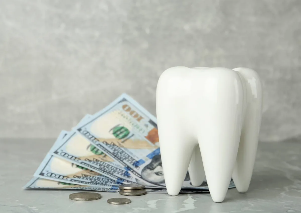 Tooth model with money representing the cost of tooth contouring and cosmetic dental treatment.