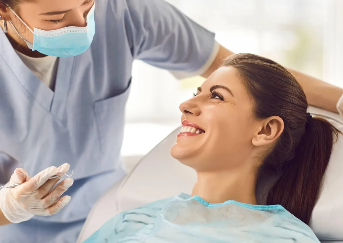 Smiling woman consulting with a dental professional about cosmetic dentistry treatments, procedures, and associated costs.