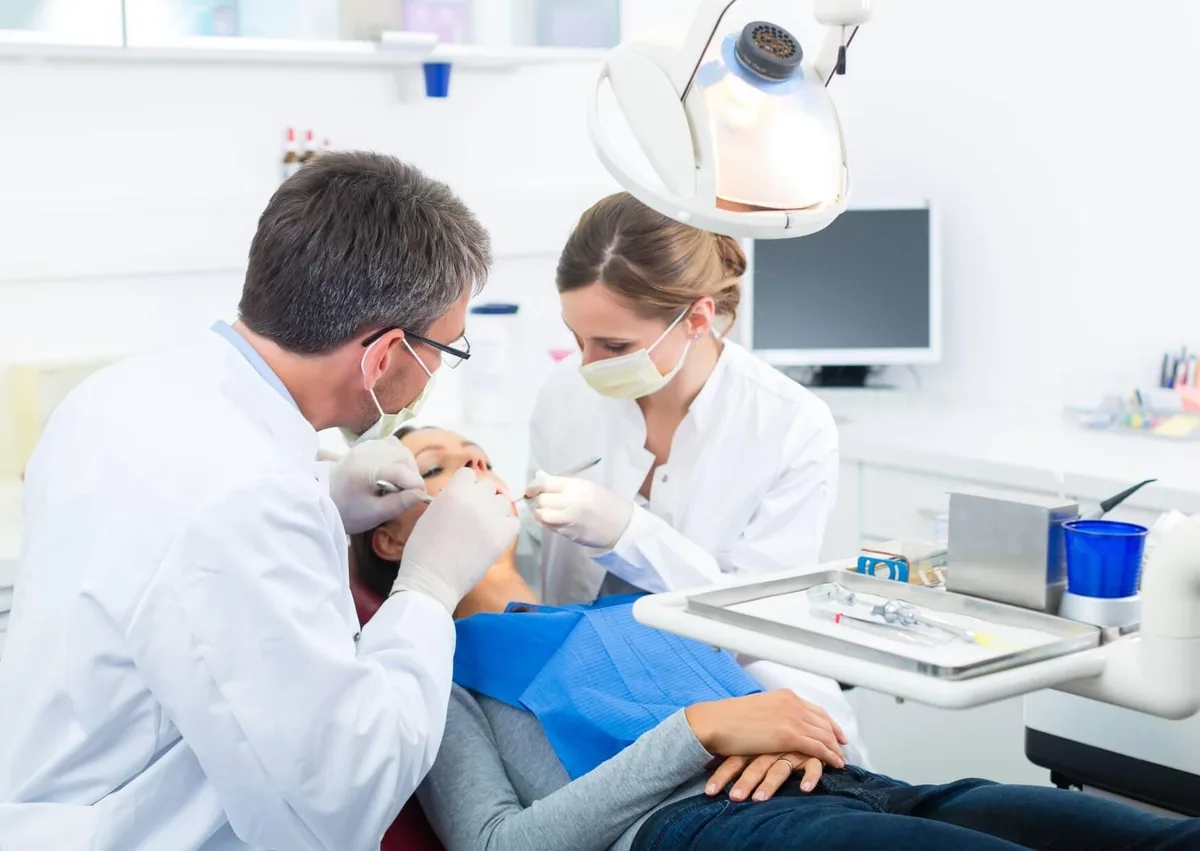 Dentist and dental assistant examining a patient's teeth to check for visible signs of cavities and tooth decay.